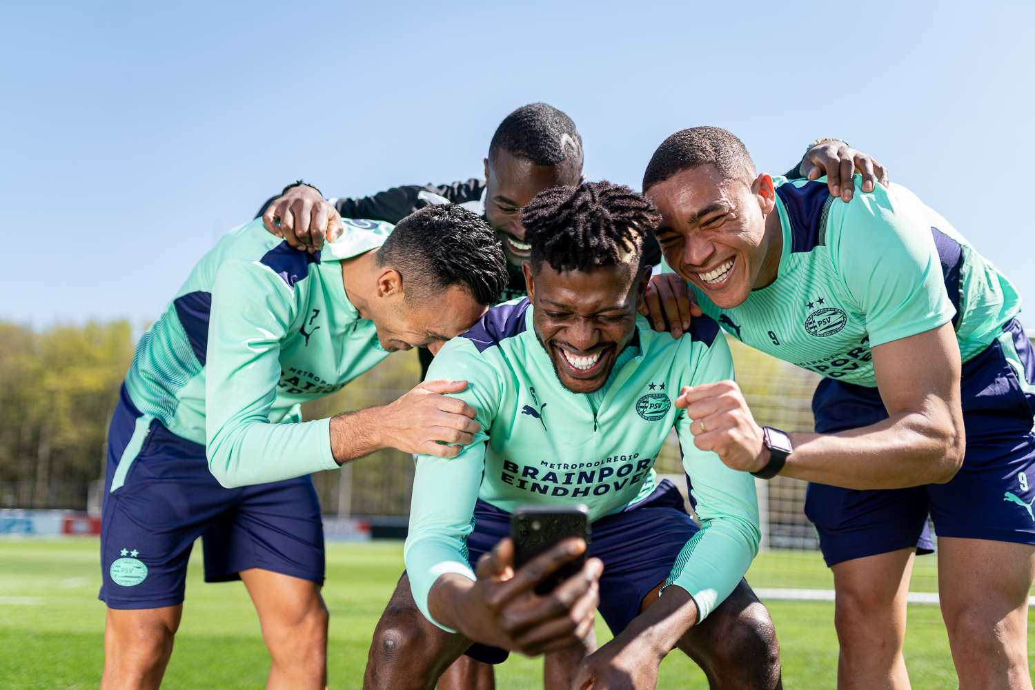Lachende PSV spelers tijdens een fotoshoot voor Anycoin Direct